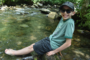 picture of a little boy dipping his feet in the river